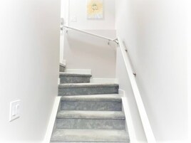 Una escalera con barandilla y un aplique en la pared.