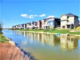 Fila de casas modernas a lo largo de un río tranquilo con cielo despejado.