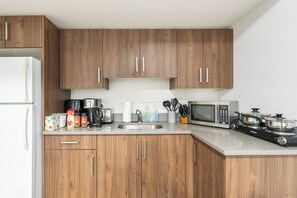 Cocina con armarios de madera, un refrigerador, un microondas, un tostador y diversos utensilios de cocina.