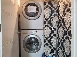 Un área de lavandería con dos lavadoras, una encima de la otra, y una cortina estampada.