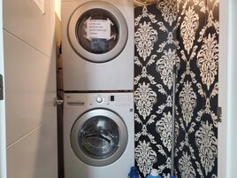 Un área de lavandería con dos lavadoras, una encima de la otra, y una cortina estampada.