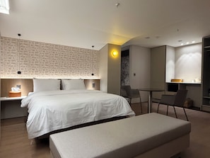 Ein modernes Hotelzimmer mit einem großen Bett, Nachttischen, einem Schreibtisch und einem Sessel.