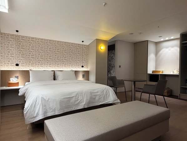 A modern hotel room with a large bed, bedside tables, a desk, and a chair.