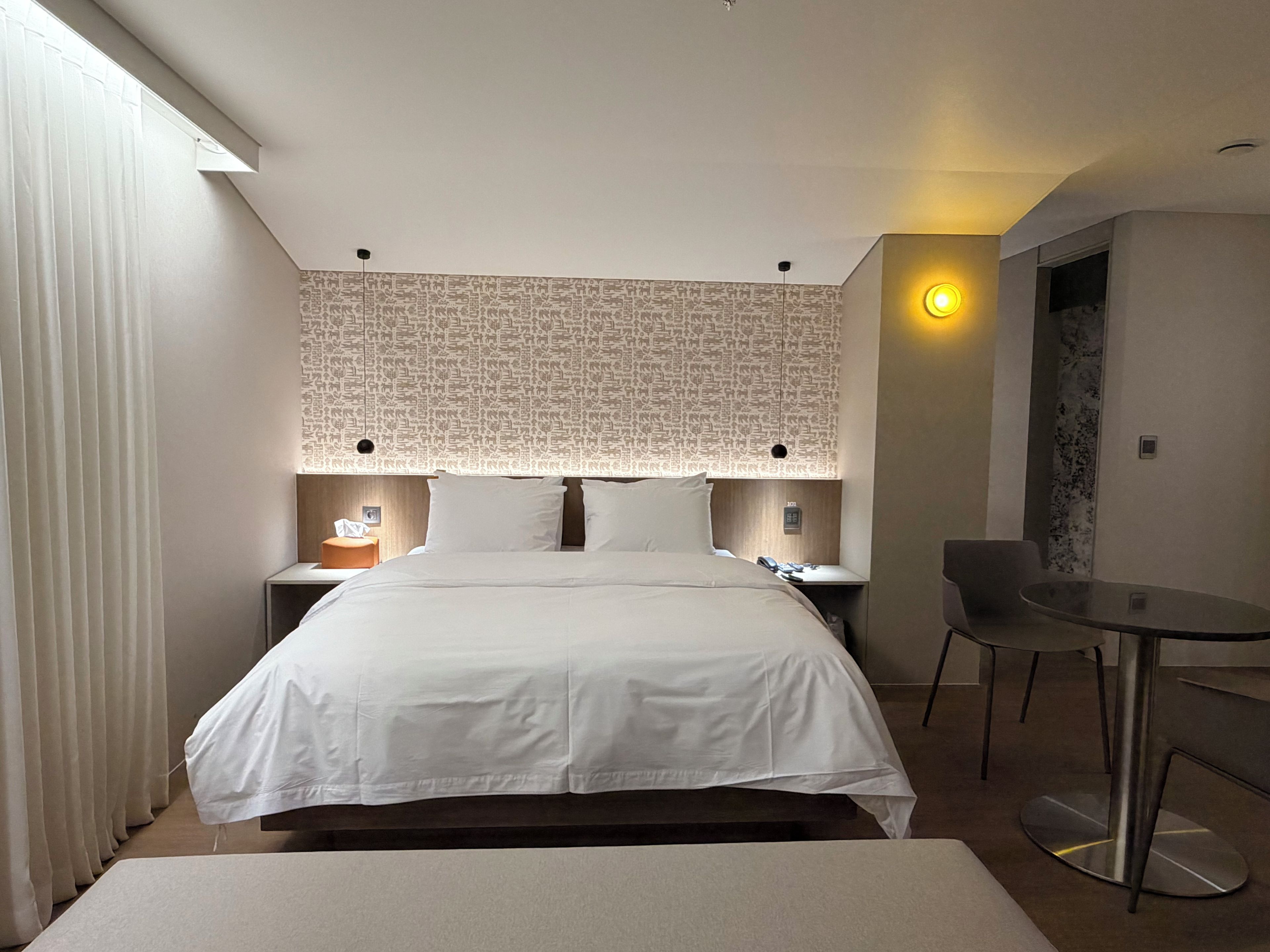 Ein Hotelzimmer mit einem großen Bett, einem Schreibtisch, einem Stuhl und einer Wand mit Muster.