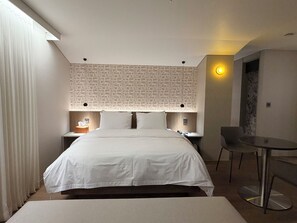 Una habitación de hotel con una cama grande, un escritorio, una silla y un papel tapiz estampado.