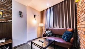 Una sala moderna con un sofá de cuero, una mesa de centro de vidrio, una lámpara y una pared de ladrillo.
