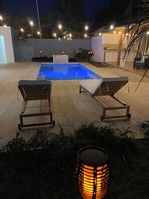 A swimming pool with two lounge chairs and a decorative lamp. - Villa del Carmen 4BR Pool Villa, 3-Min Walk to Beach & River (Cabrera)