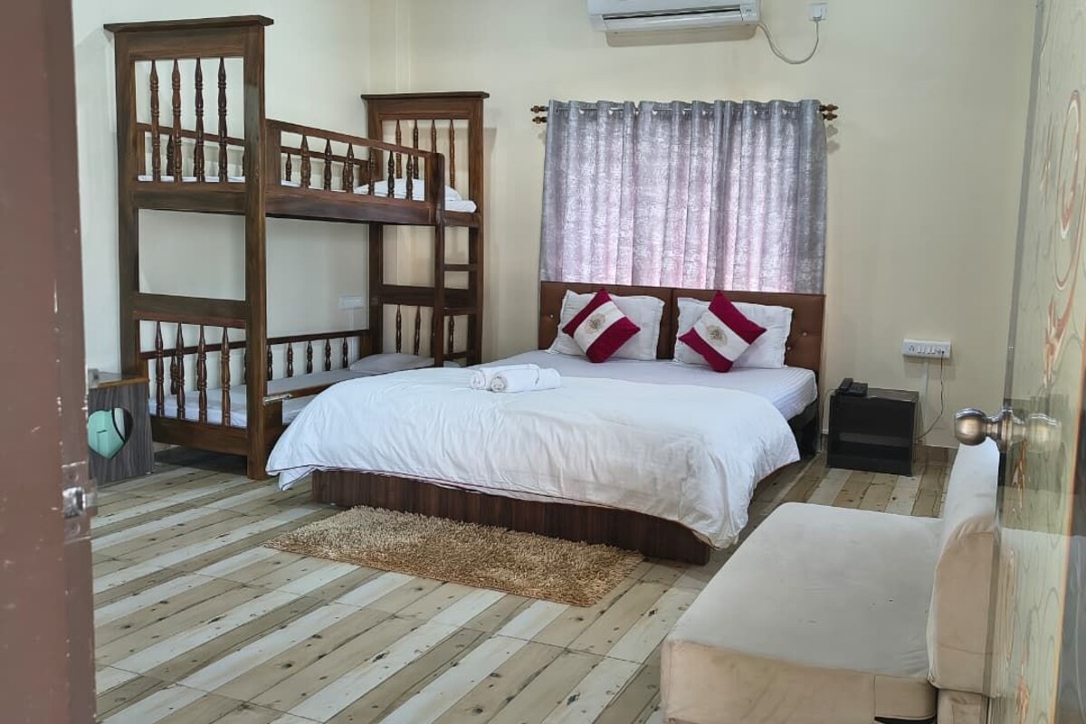 Quarto com cama beliche, mesa de cabeceira, cadeira, janela com cortinas e ar condicionado.