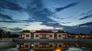 Um edifício tradicional refletido em águas calmas, rodeado por uma vedação.