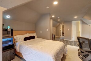 Ein Schlafzimmer mit Bett, Schreibtisch, Stuhl und begehbarem Kleiderschrank.