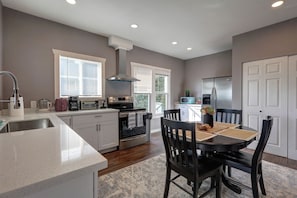 A modern kitchen with a central island, built-in oven, and a dining area with a round table and chairs. - 4B2B DT Everett Ideal for Medical/Corporate/Insurance Placement close Hospital (Everett)