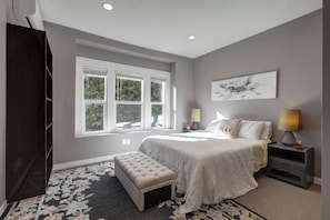 A bedroom with a bed, a bench, a nightstand, a lamp, and a window with blinds. - 4B2B DT Everett Ideal for Medical/Corporate/Insurance Placement close Hospital (Everett)