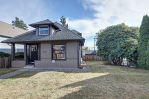 Ein eingeschossiges Haus mit einer überdachten Veranda, einer kleinen Garage und einem gepflegten Rasen.