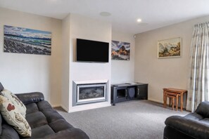 Een woonkamer met een open haard, een flatscreen televisie en kunst aan de muren.