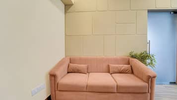 A modern living room with a pink sofa, a wooden floor, and a wall with a geometric pattern.