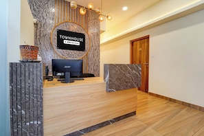 A reception desk with a computer, a sign reading 'TOWNHOUSE YOYO-Serviced,' and a wooden door marked with the number 110.