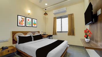 A hotel room with a bed, bedside table, lamp, artwork, air conditioning unit, window with curtains, and a TV.
