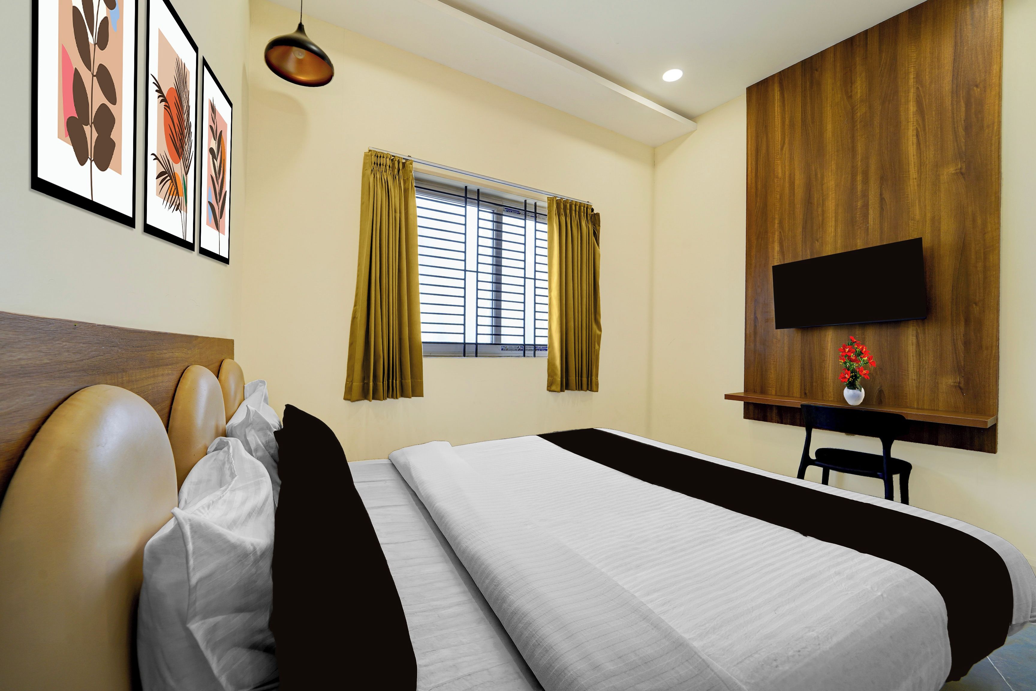 Una habitación de hotel con una cama, un televisor montado en la pared, una ventana con cortinas y cuadros enmarcados en la pared.