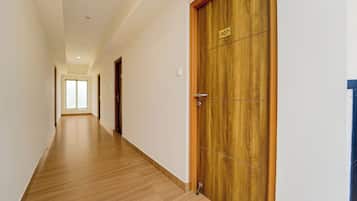 A hallway with wooden flooring and a wooden door with a number plate.