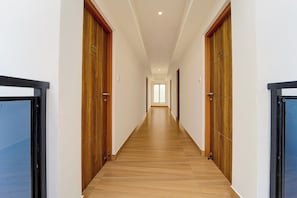 A long, narrow hallway with wooden doors on both sides and a wooden floor.