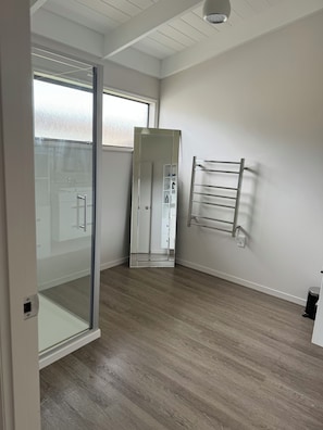 A room with a glass door leading to a shower area, a white wardrobe, and a towel rack on the wall. - Quaint 3-bedroom house in welcoming Omaha neighborhood (Omaha)