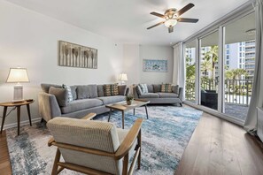 A modern living room with a grey sofa set, a striped armchair, a coffee table, and a ceiling fan. - Poolside Paradise Resort Pool (Destin)