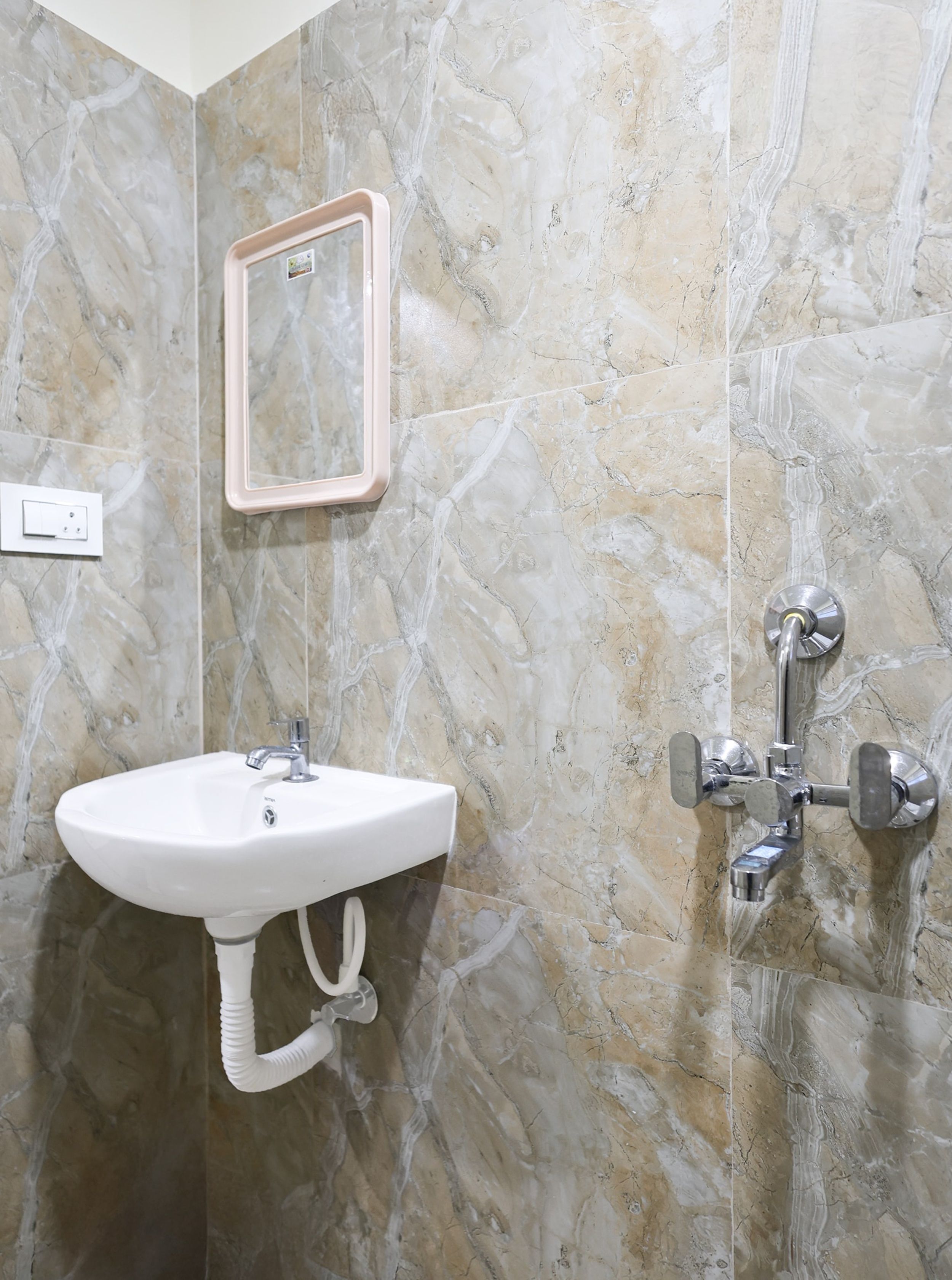 A bathroom with a white sink, a mirror, and a shower with a chrome faucet.