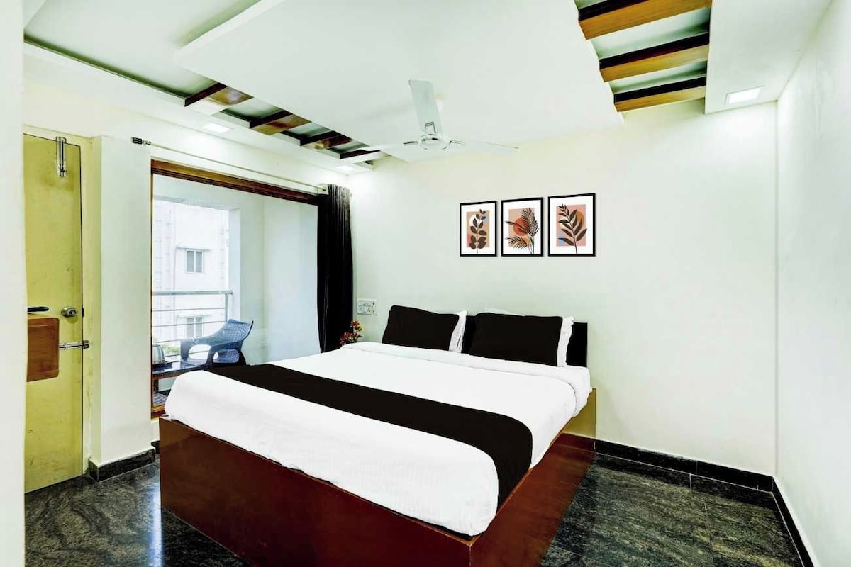 Una habitación de hotel con una cama, un ventilador de techo y obras de arte enmarcadas en la pared.