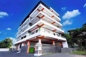 Un edificio de varios pisos con balcones, una puerta verde y una cerca.