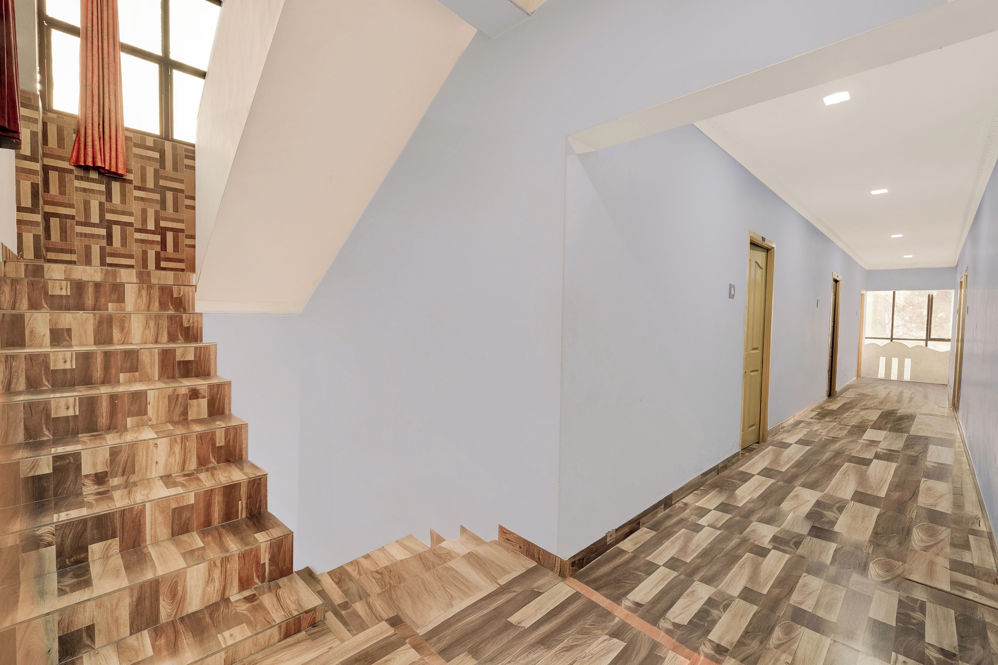 A hallway with a wooden staircase and a patterned floor.