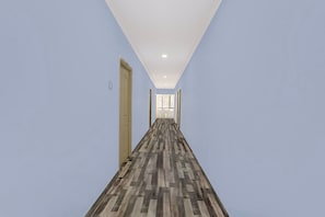 A hallway with a patterned floor, light blue walls, and doors on both sides.