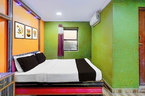A hotel room with a bed, a window with curtains, and a door.
