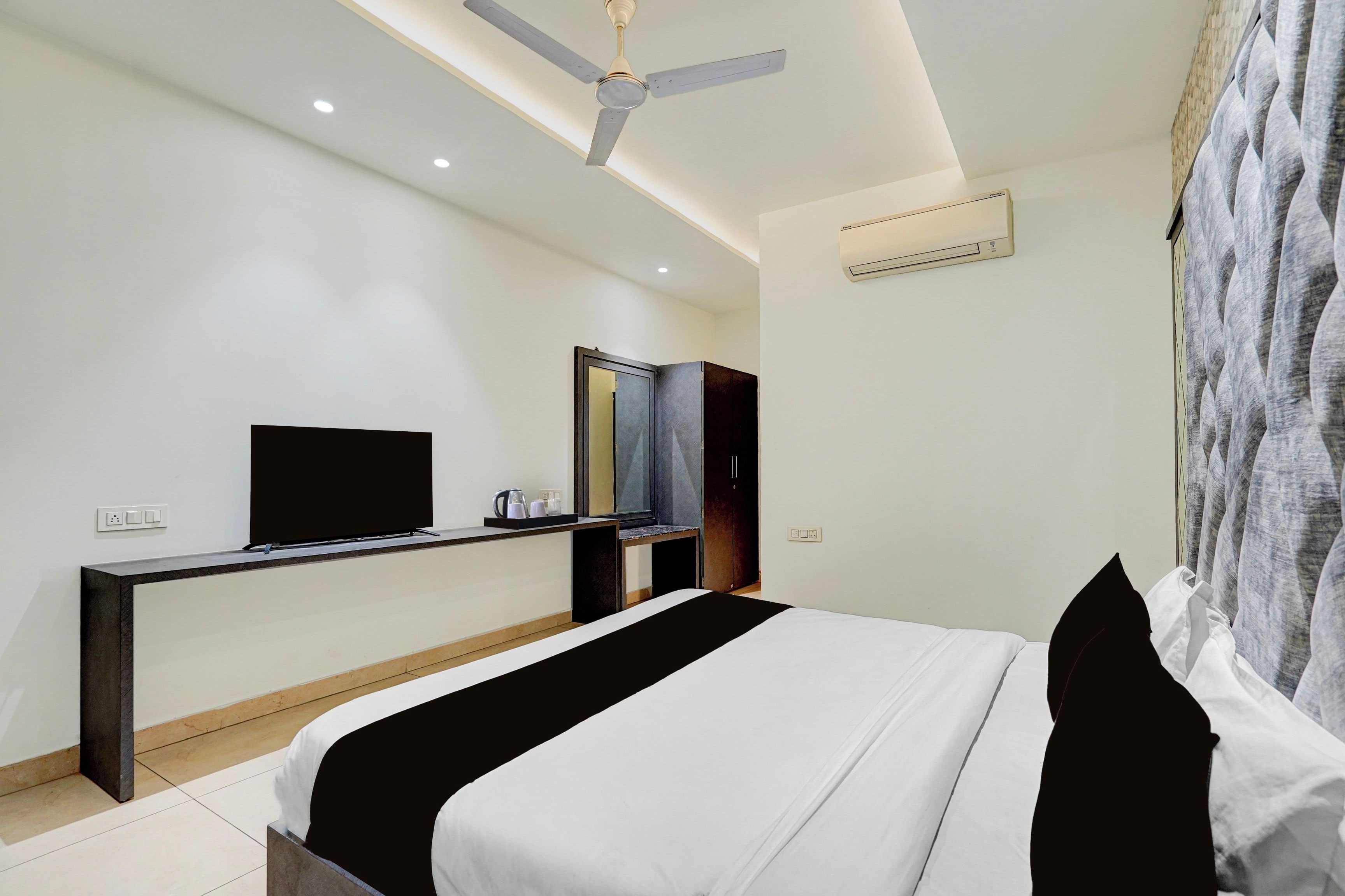 A hotel room with a bed, a TV, a desk, and a wardrobe.