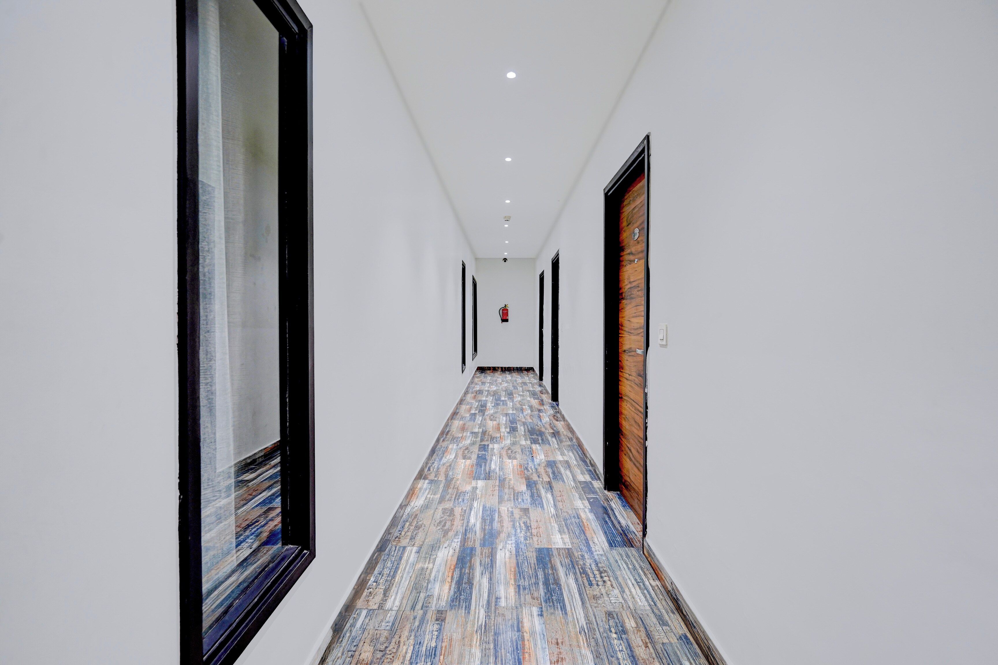 A hallway with a patterned floor, white walls, and doors on both sides.