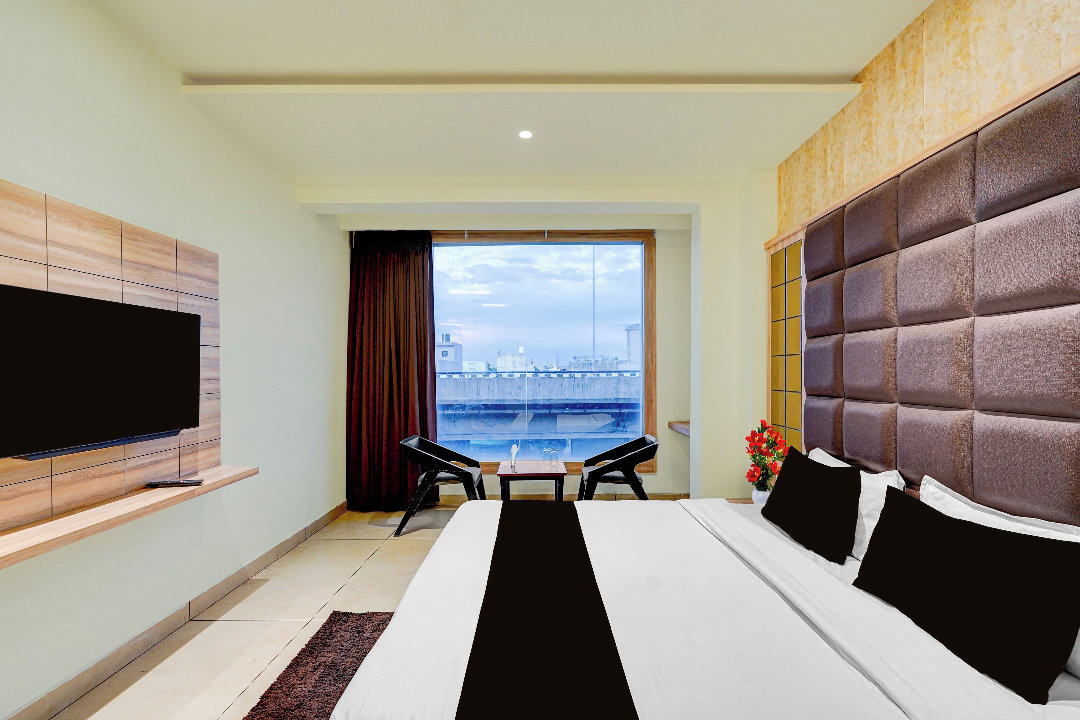 Habitación de hotel con cama, televisión, vista a un puente y una mesa con sillas.