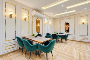Une salle de conférence avec une longue table, des chaises de couleur turquoise et des luminaires fixés au mur.