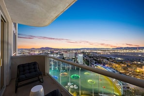 A balcony with a city view, a chair, and a pool area with circular lights. - Palace in the Sky|Vegas Strip Balcony/Sphere/Pools (Las Vegas)
