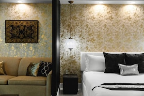 A hotel room with a bed, a sofa, a wall-mounted lamp, and a framed artwork. - Palace in the Sky|Vegas Strip Balcony/Sphere/Pools (Las Vegas)