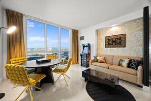 A modern living room with a sofa, a coffee table, and a dining area with chairs and a table. - Palace in the Sky|Vegas Strip Balcony/Sphere/Pools (Las Vegas)