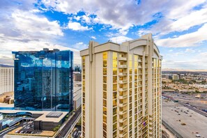 A high-rise hotel with multiple floors, a modern glass facade, and a parking area with a view of the surrounding cityscape. - Vegas Sky Suite | Extended Balcony + Strip Views (Las Vegas)