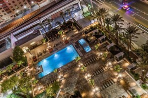 A rooftop pool area with multiple lounge chairs and a swimming pool, surrounded by palm trees and outdoor lighting. - Modern Vegas Escape|Private Balcony+Strip Views! (Las Vegas)