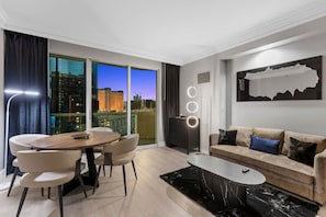 A modern living room with a dining area, a sofa, a coffee table, and a city view through large windows. - Modern Vegas Escape|Private Balcony+Strip Views! (Las Vegas)