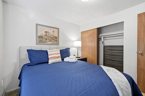 Une chambre à coucher avec un lit, une table de chevet, une lampe et une armoire en bois.