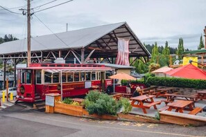 A red bus with a covered seating area and outdoor tables and benches. - Serene & Wooded Retreat | Shops & Waterfront (Gig Harbor)