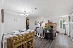Un coin repas avec une table en bois, des chaises et une horloge au mur.