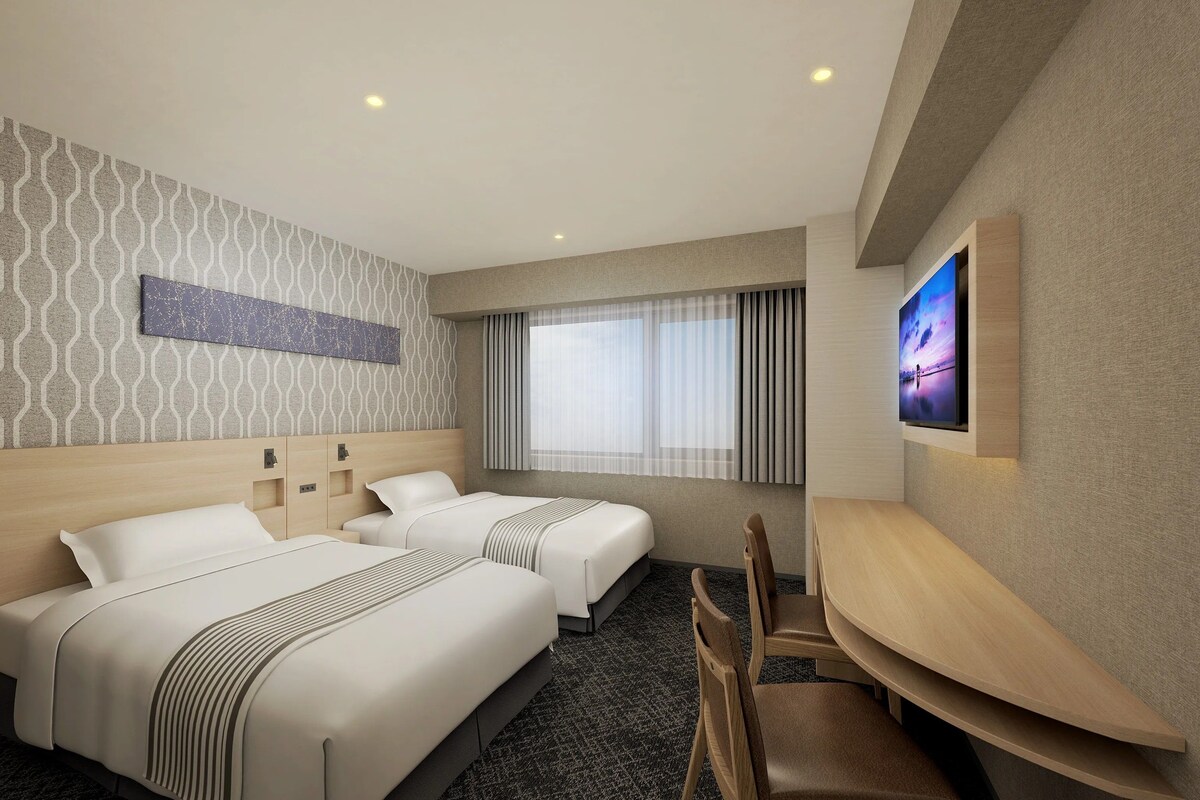 A hotel room with two beds, a TV, and a seating area.