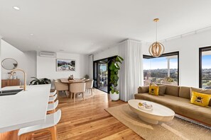 A modern living room with a sofa, coffee table, and dining area. - Elevated Luxury (Geelong)