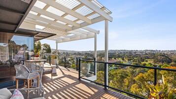 A balcony with a view of a cityscape, furnished with wicker chairs and a table.