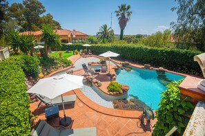 A swimming pool with a curved design, surrounded by a patio area with seating and umbrellas. - Boutique Villa Marcia—Adults Only, 10 minutes from the beach. (Altafulla)