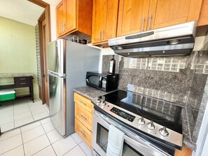 A kitchen with a stainless steel refrigerator, a microwave, an oven, and a gas stove. - Prime Waikiki 1BR | Free Parking, Pool & W/D (Honolulu)